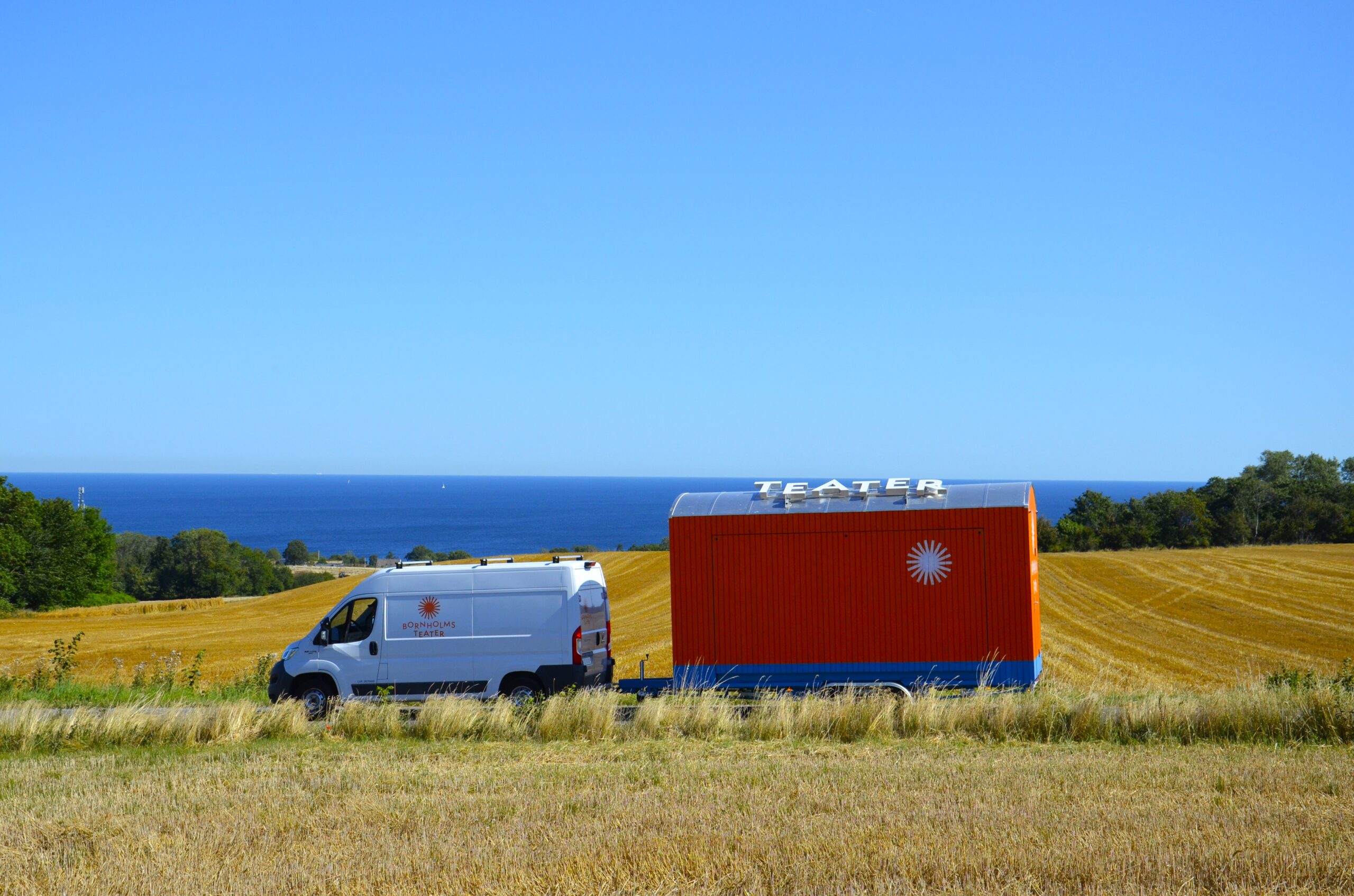 Solskinsteatret er bygget op omkring en mobil teaterscene i form af en trailer, hvor den ene langside kan slås ned og fungere som scene. Den blev et hyppigt syn på de bornholmske landeveje i sommeren 2025. Foto: Kim Caspersen/Bornholms Teater.